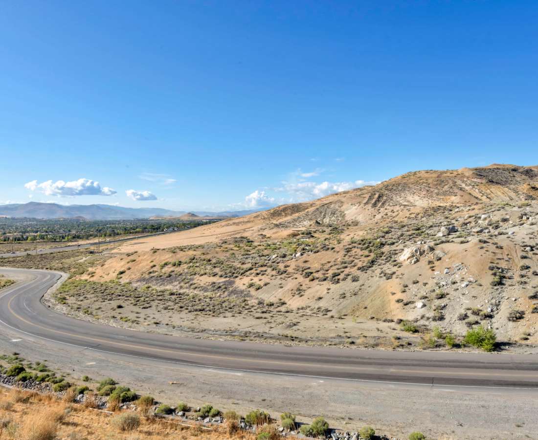 A scenic highway stretches through the desert, framed by majestic mountains in the background at Prosper 83 in Sparks, Nevada