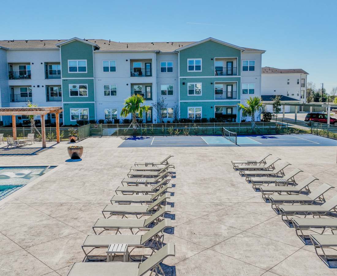 Lounge chairs beside tennis courts at apartment community at Meridian City Park in Houston, Texas