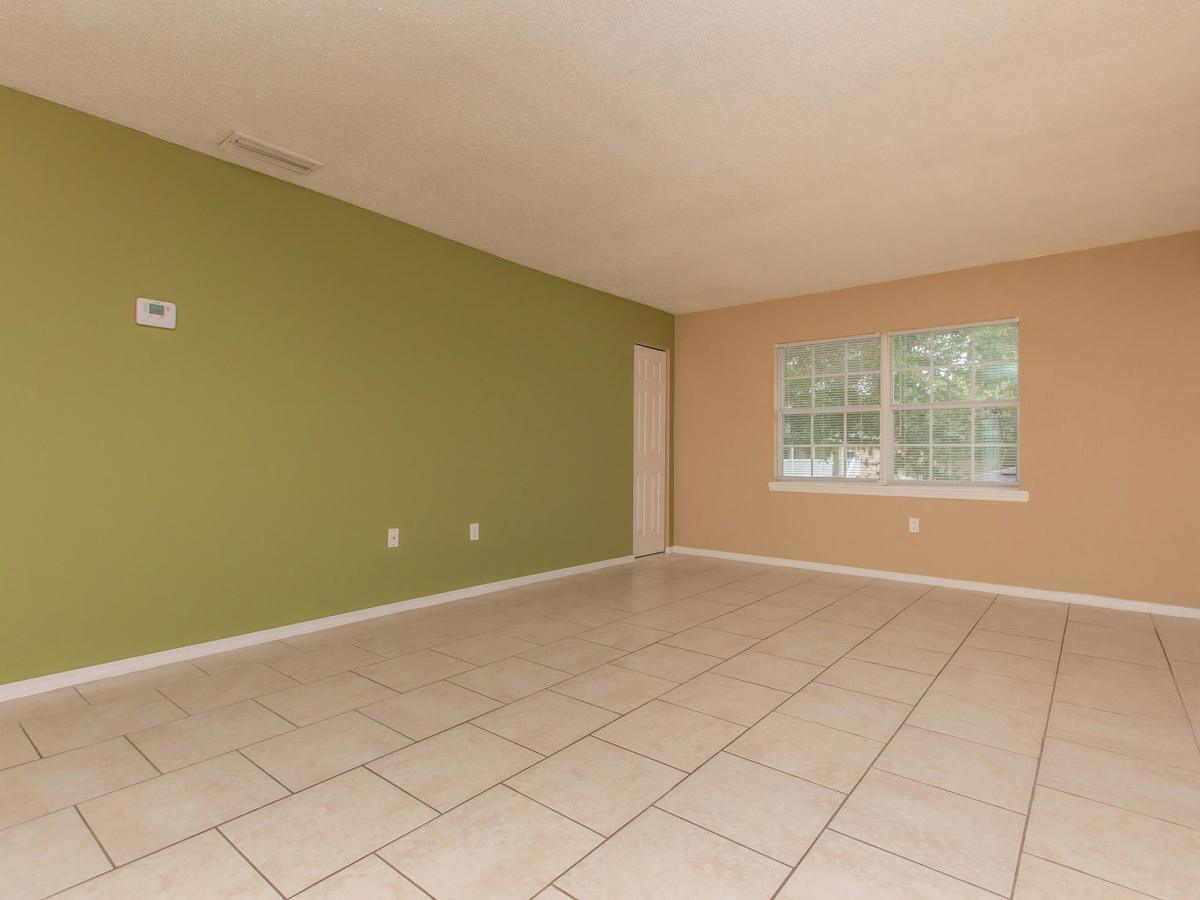 Living room with ceramic tile floor and window at Serenity Apartments in Leesburg, Florida