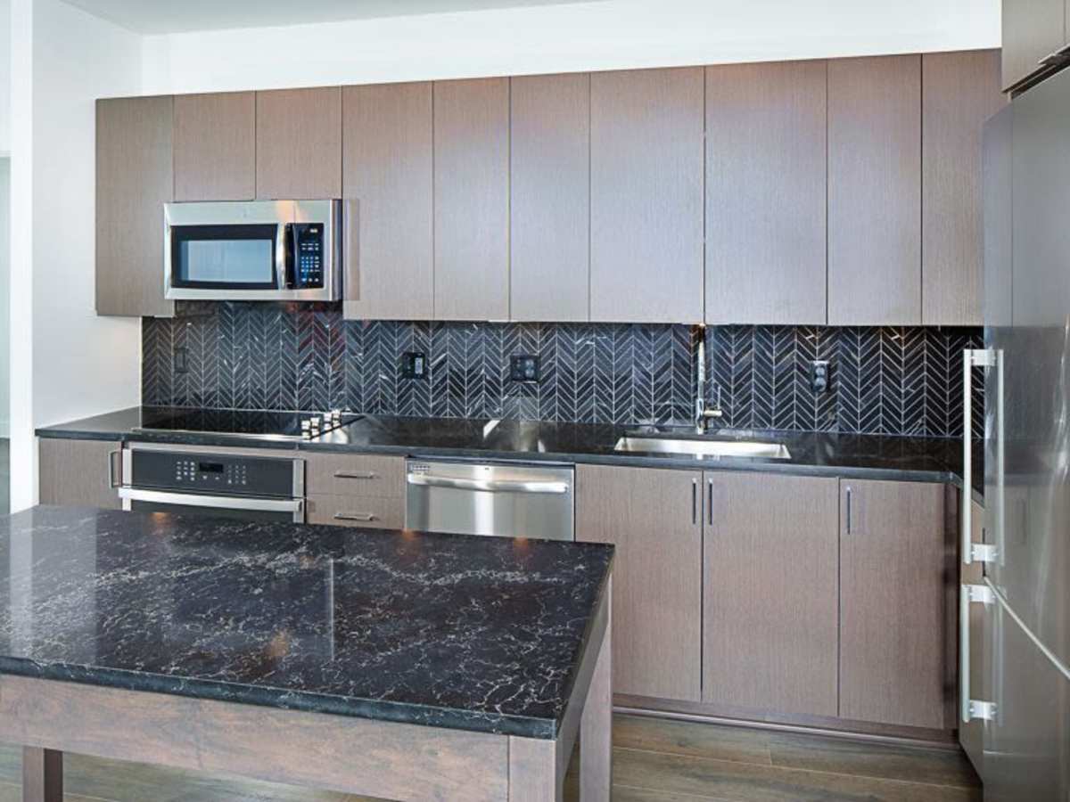 Kitchen with a dark tile backsplash and dark countertops at J Linea in Washington, District of Columbia