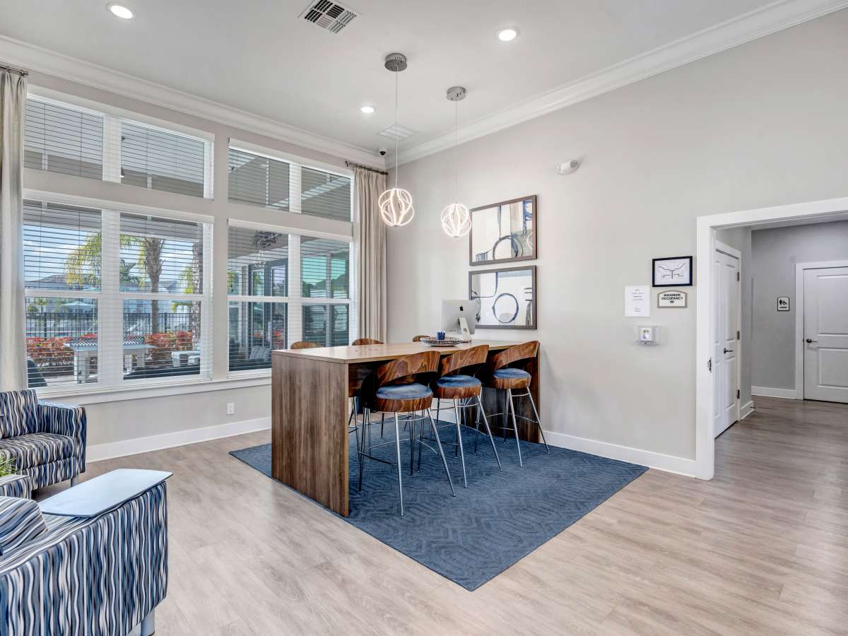 Bright community lounge with modern bar seating, large windows, and stylish decor at The Carlton of West Melbourne in West Melbourne, Florida