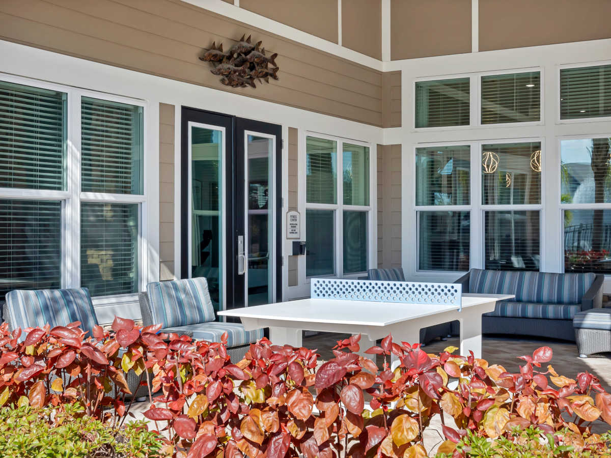 Outdoor lounge area with striped seating and vibrant landscaping, perfect for relaxation and socializing at The Carlton of West Melbourne in West Melbourne, Florida
