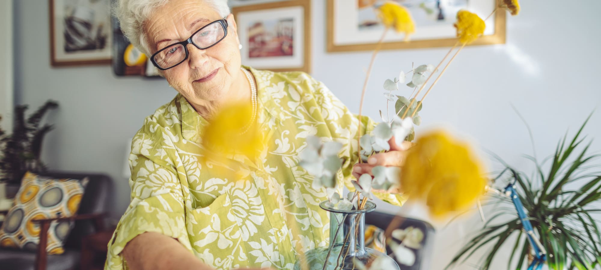 Woman in yellow shirt arranging yellow flowers in her apartment