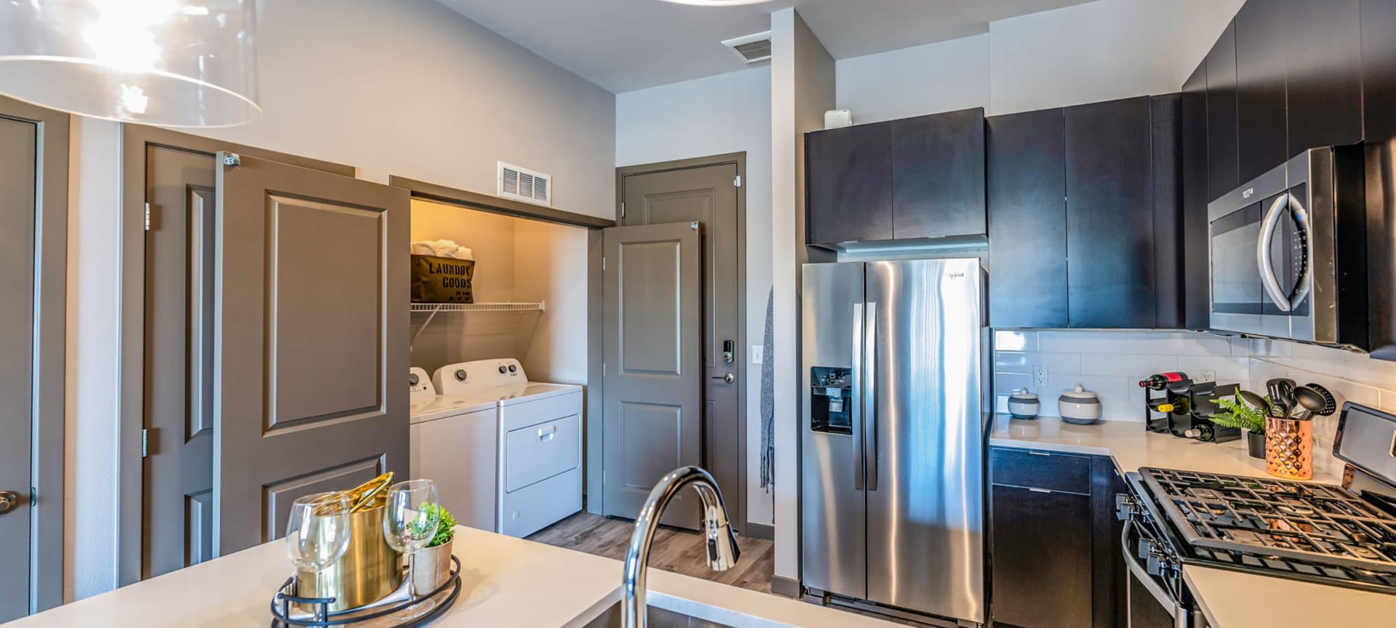 Open-concept model home's kitchen with quartz countertops and a view of the living area at Jade Apartments in Las Vegas, Nevada