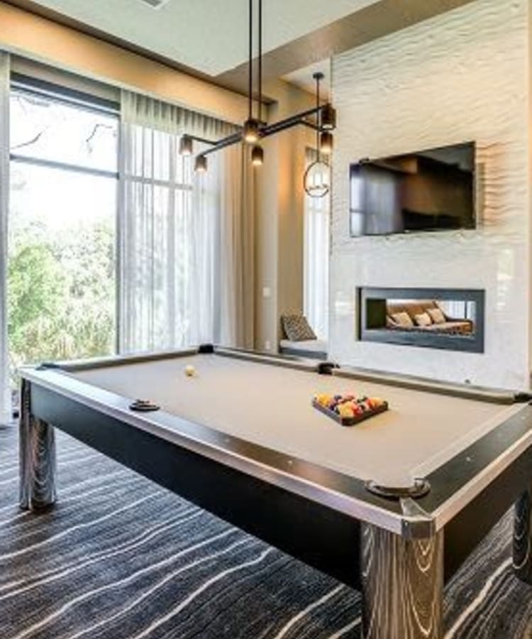 Community clubhouse with pool table and flatscreen television at Addison at Tampa Oaks in Temple Terrace, Florida