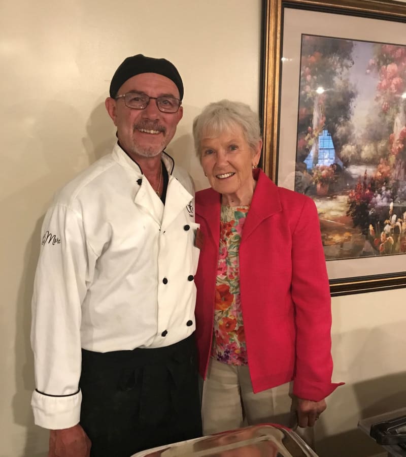 A chef and a resident arm-in-arm smiling for a photo at a Hearth Management community