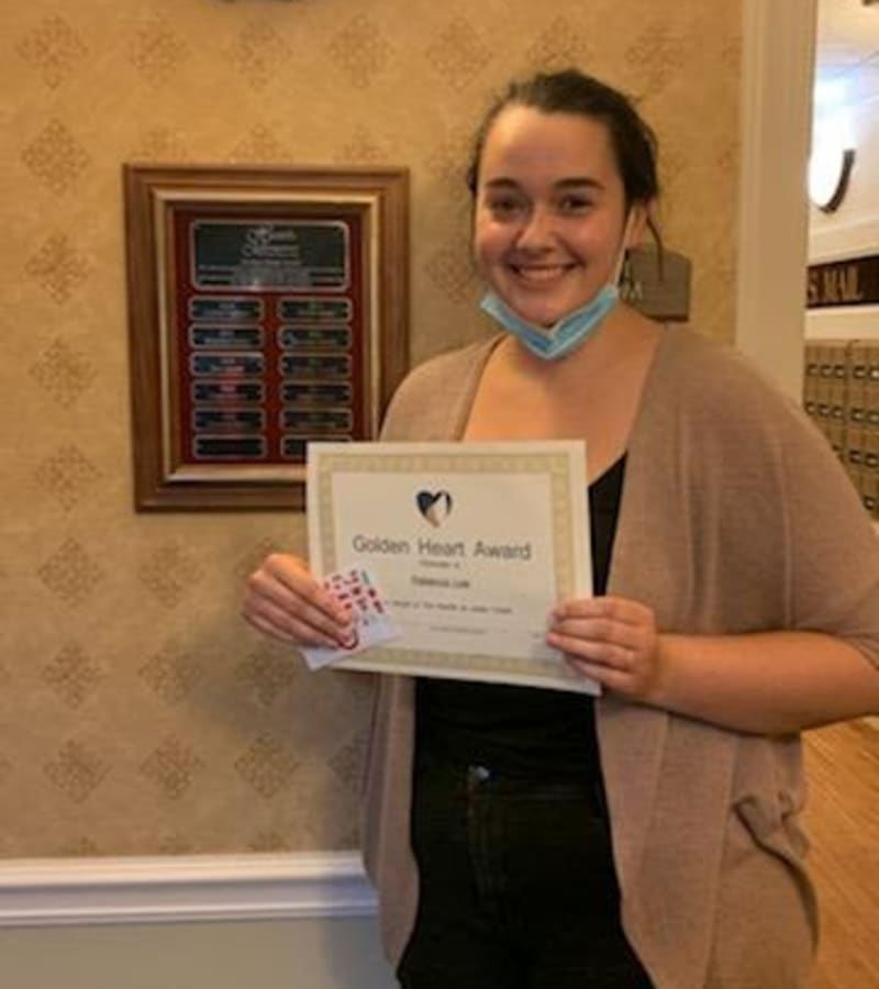 A caretaker posing with her Golden Heart Award at a Hearth Management community