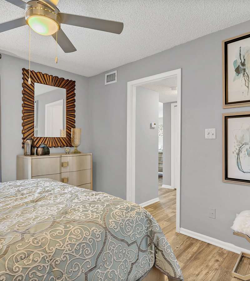Bedroom with a comfortable bed, large windows and a dressing table with a mirror on the wall at Rosemont Windermere in Orlando, Florida