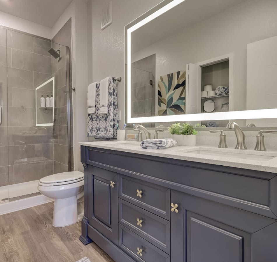Double vanity of an apartment bathroom and a glass shower at The Vivien in Vero Beach, Florida