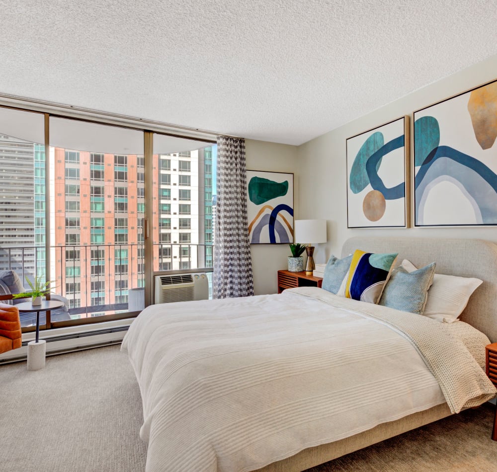 Well-furnished model home's primary suite with floor-to-ceiling windows and a terrific view of the city at Tower 801 in Seattle, Washington