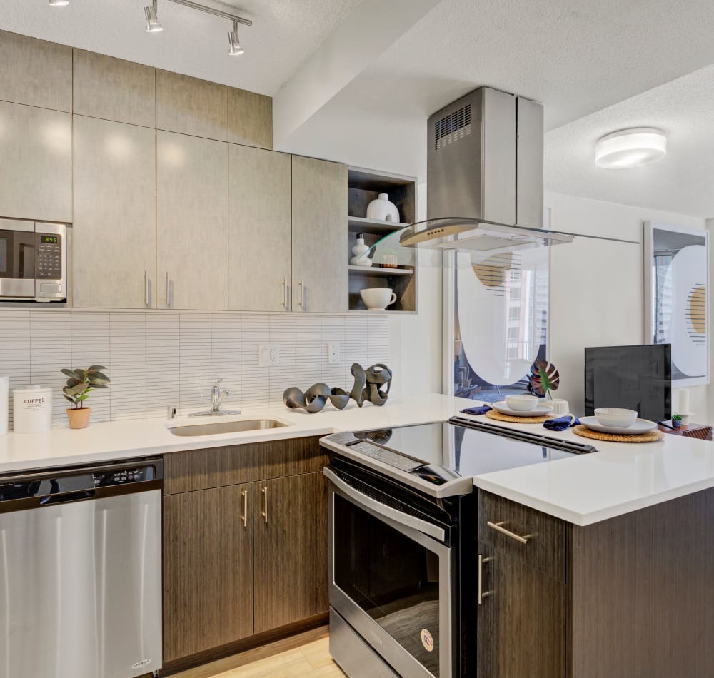 Modern kitchen with quartz countertops and rich, dark wood cabinetry in a model home at Tower 801 in Seattle, Washington