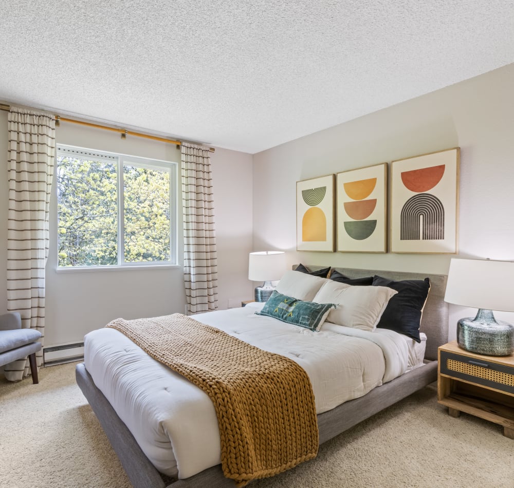 Large bedroom with forest views and large amounts of natural light in a model home at Haven Apartment Homes in Kent, Washington