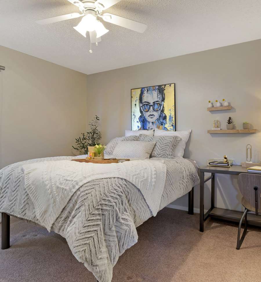 Carpeted furnished bedroom with ceiling fan at The Landing at College Station in College Station, Texas