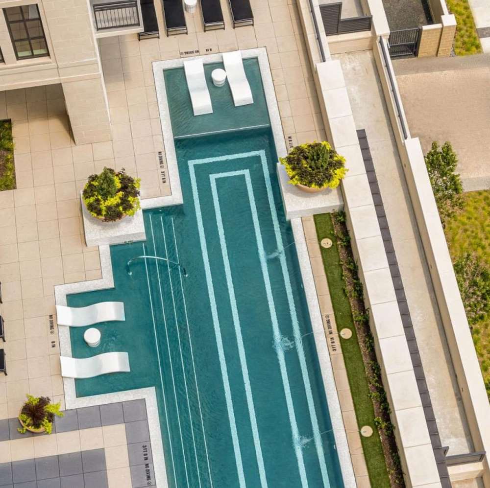 Aerial view of a resort-style pool with lounge chairs at Novel Turtle Creek in Dallas, Texas