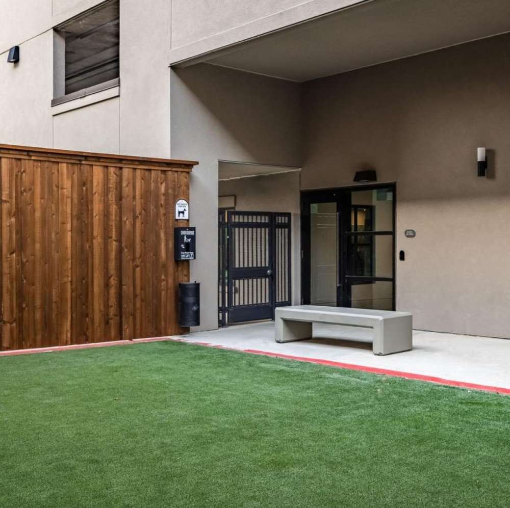 Gated entrance with artificial grass and wooden fence at Novel Turtle Creek in Dallas, Texas
