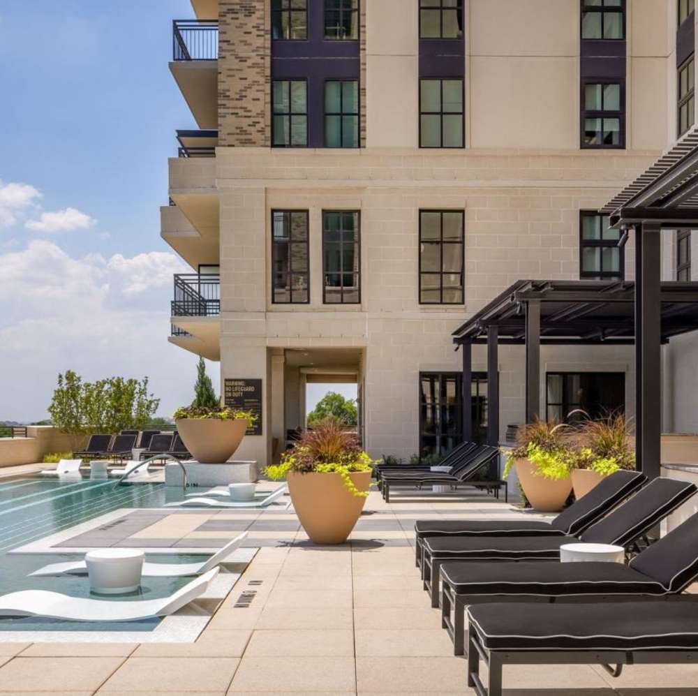 Resort-style pool with lounge chairs and planters at Novel Turtle Creek in Dallas, Texas