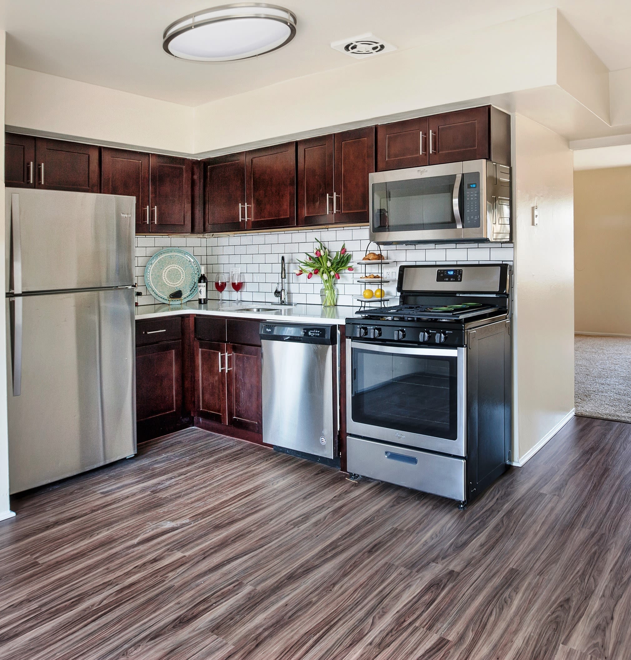 model kitchen with stainless-steel appliances and wood style flooring at Franklin Commons in Bensalem, Pennsylvania