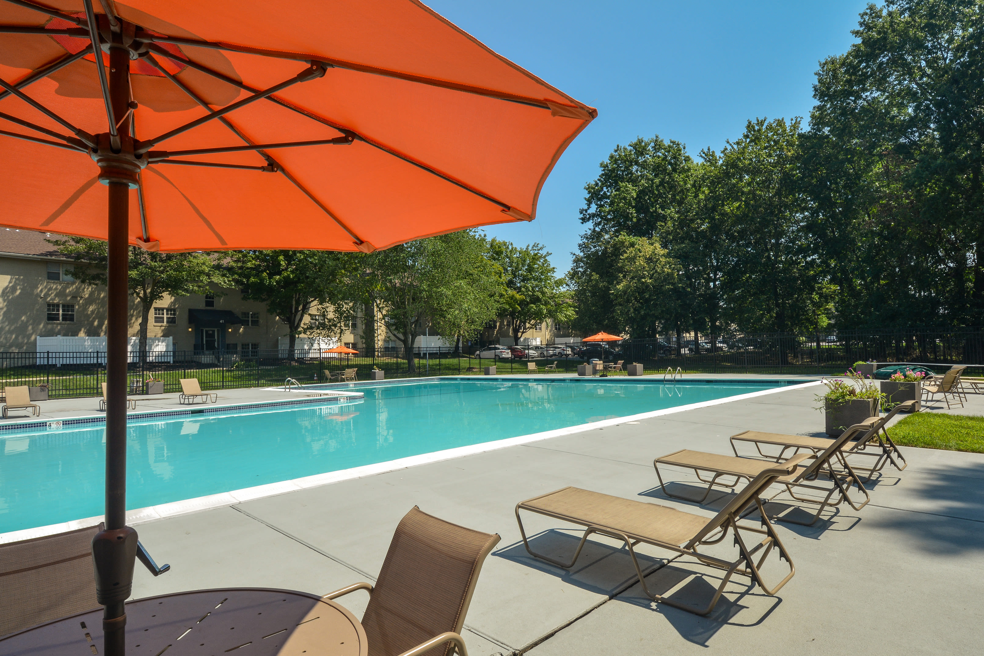 Sparkling pool with lounge chairs and umbrella at Hunters Crossing, Newark, Delaware