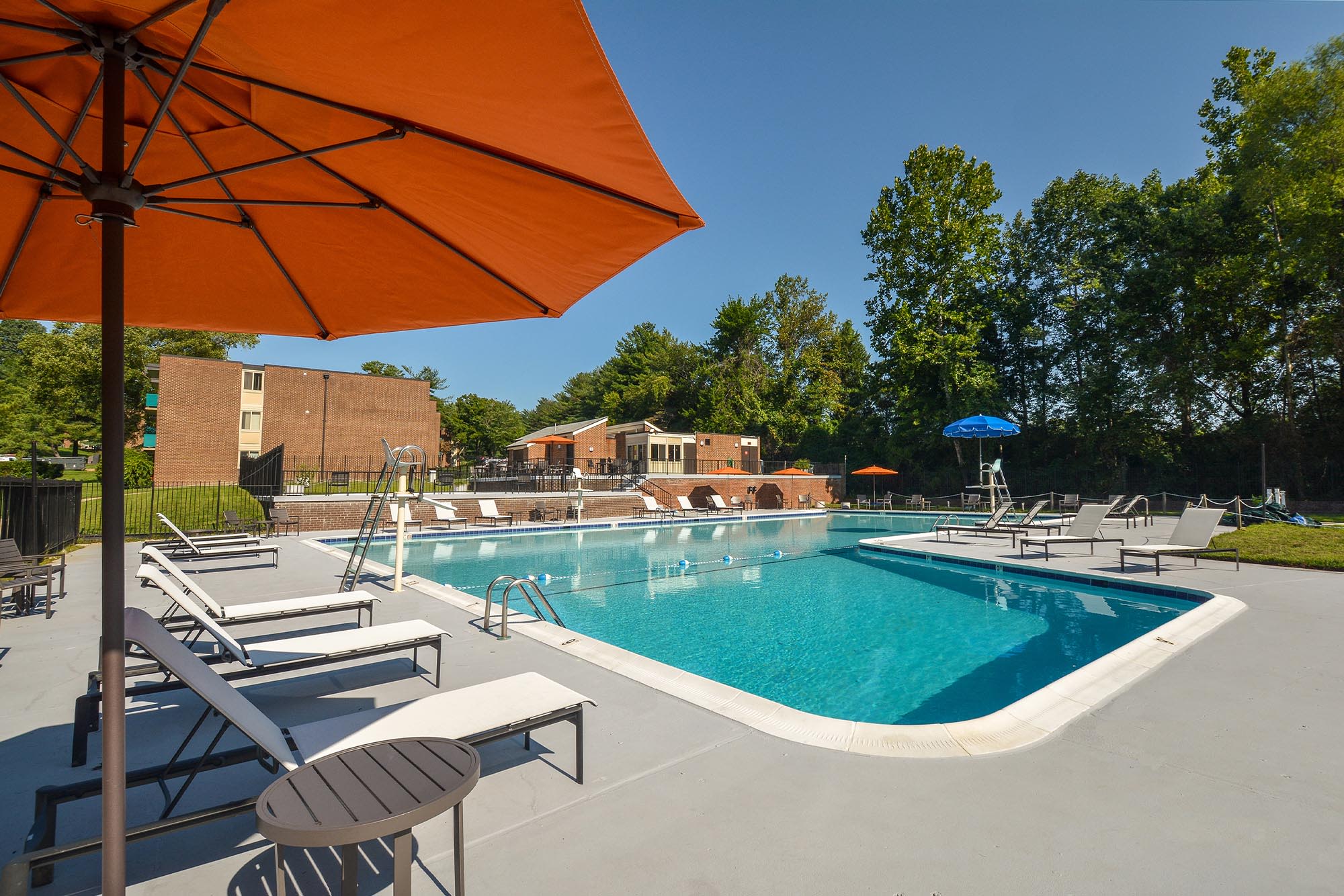 Swimming pool with lounge chairs and umbrellas at Landmark Glenmont Station in Silver Spring, Maryland