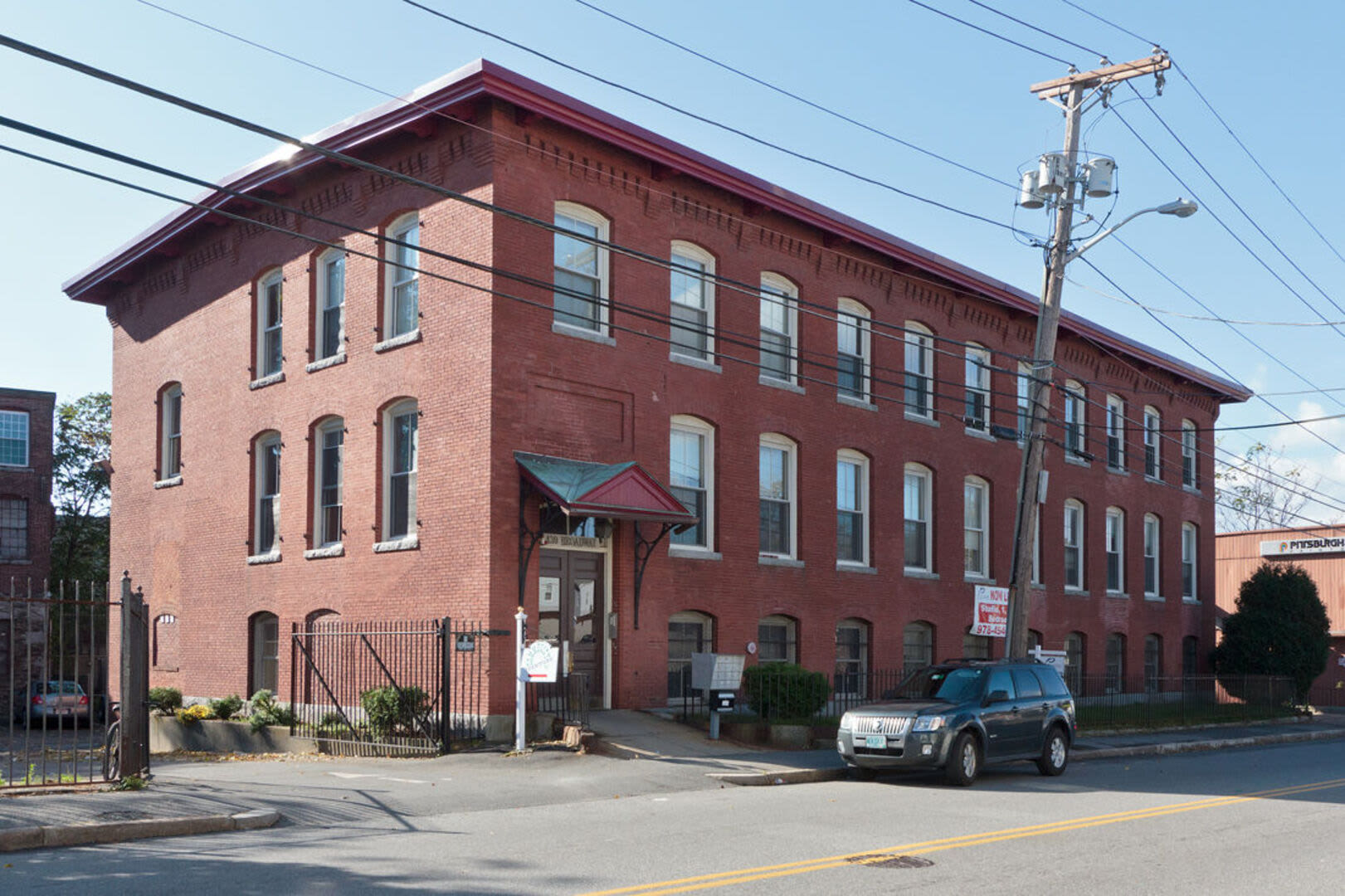Community building with a car parked in front at Broadway Street Apartments in Lowell, Massachusetts