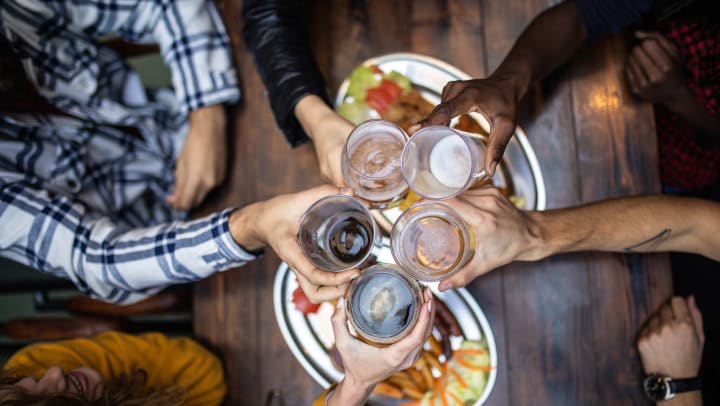 High view of five people toasting with pints of beer