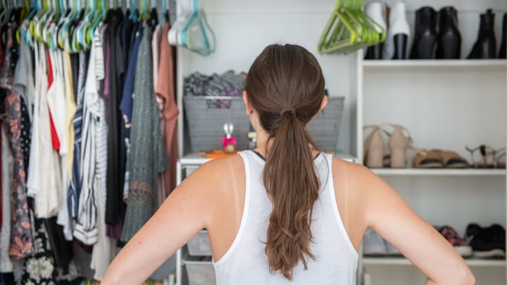 Woman standing with her hands on her hips staring at her closet