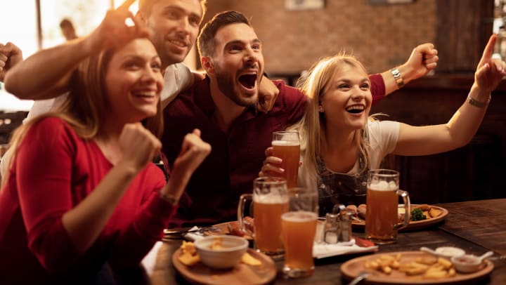Four people cheering at a bar
