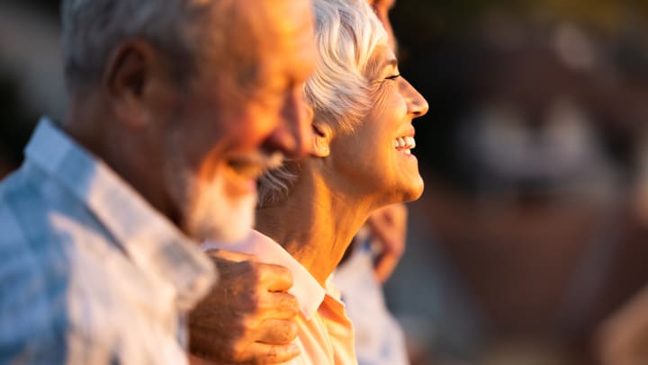Happy elderly friends laughing as they watch the sunset. 