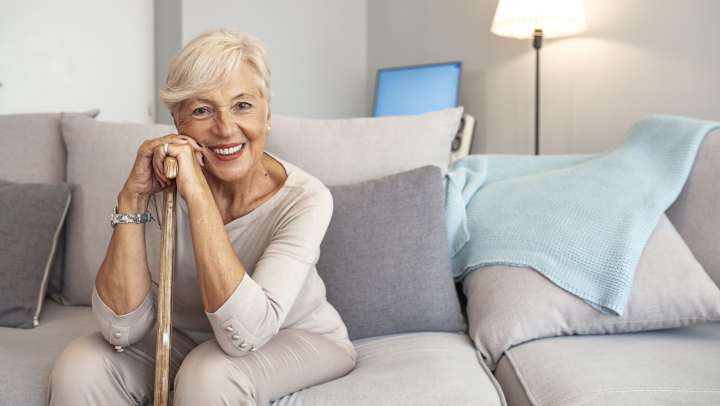 Eldely woman sitting and smiling in bedroom