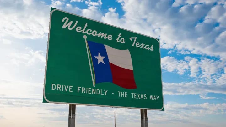 Welcome to Texas highway billboard at the state border, surrounded by blue sky and open road.