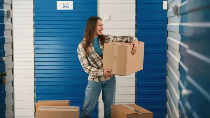 Woman holding boxes as she’s ready to store items in a storage unit