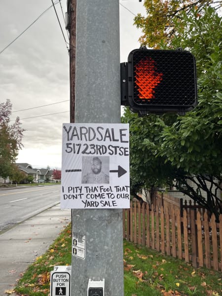 A sign advertising a yard sale on a street corner that says "I pity the fool who doesn't come to our yard sale" with a photo of Mr. T