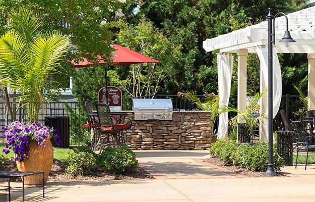 View of the firepit and outdoor barbecue area here at The Seasons at Umstead luxury apartments