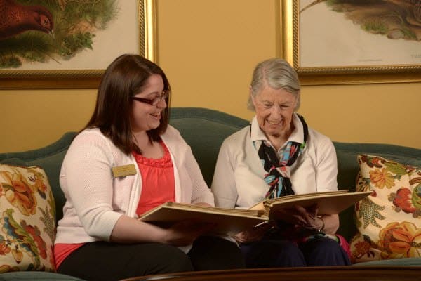 Caregiver and resident reading at Symphony at St. Augustine in St Augustine, Florida