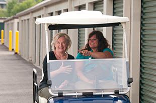 Two ladies in a golf cart touring storage units at Virginia Varsity Transfer & Storage