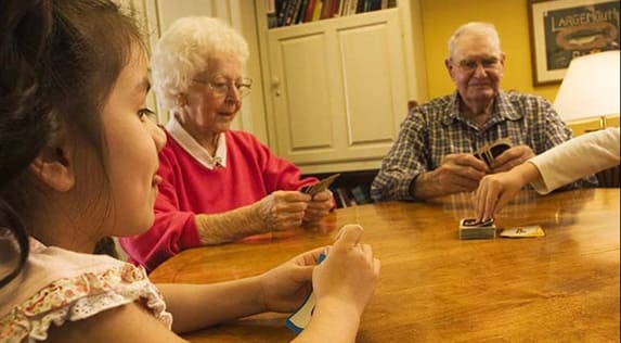 Seniors playing cards with someone's granddaughter at Regency Newcastle in Newcastle, WA