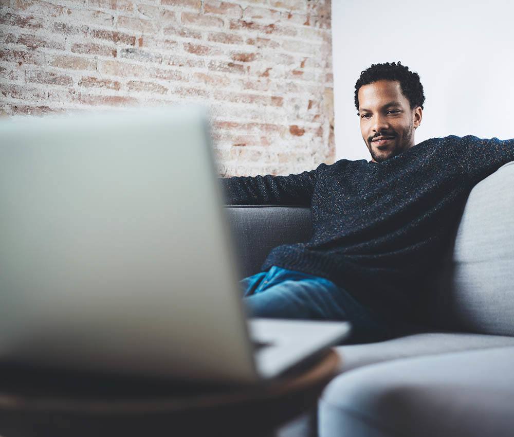 Man on couch enjoying a movie on laptop