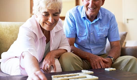 Happy couple at one of our Grand Villa Senior Living communities playing dominos