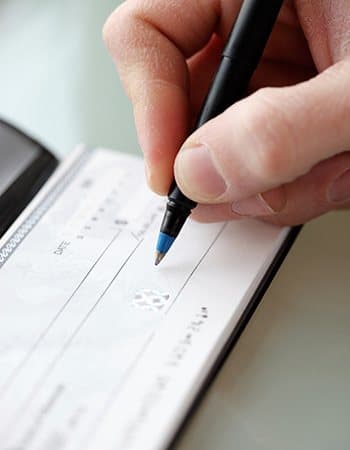 Caregiver writing a check for mom's stay at Grand Villa of Deerfield Beach in Florida
