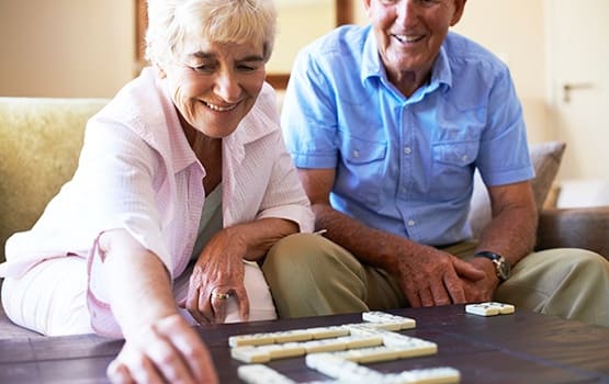 Senior couple having a ball playing backgammon as part of our Respite Care program here at Grand Villa of Clearwater in Florida