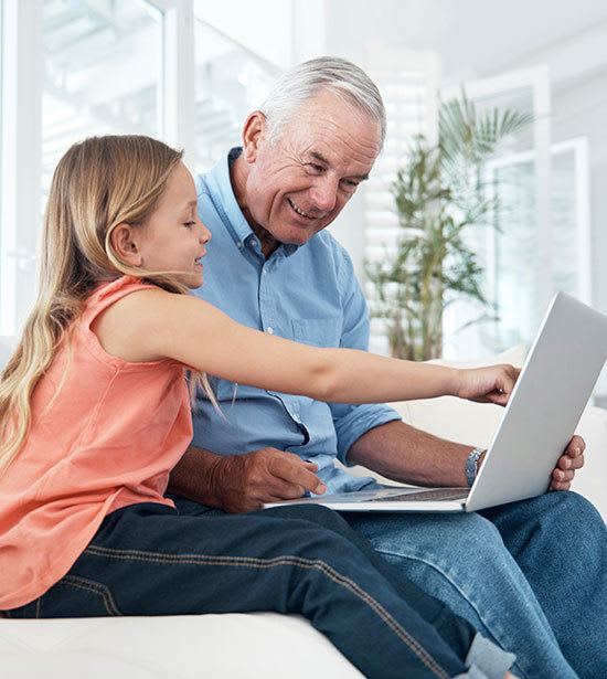 A senior living resident at Cedarbrook of Rochester and his granddaughter doing research on the computer