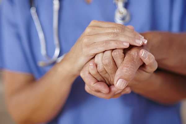 Caretaker holds the hand of a resident at Sun City Senior Living
