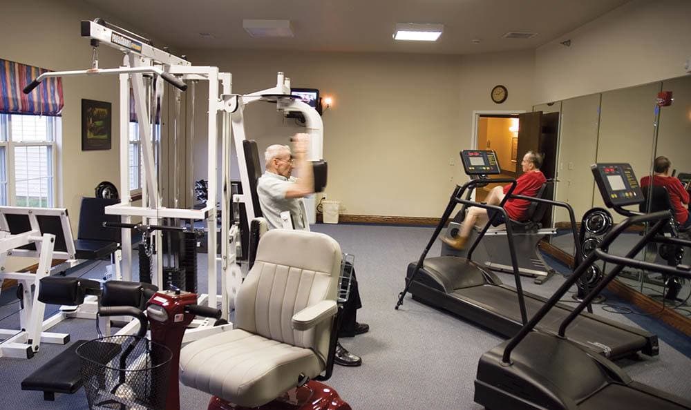 2 Residents in the fitness center using equipment at Randall Residence of Decatur in Decatur, Illinois
