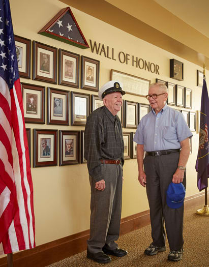 Independent living residents standing in front of military wall of honor at Sagewood at Daybreak