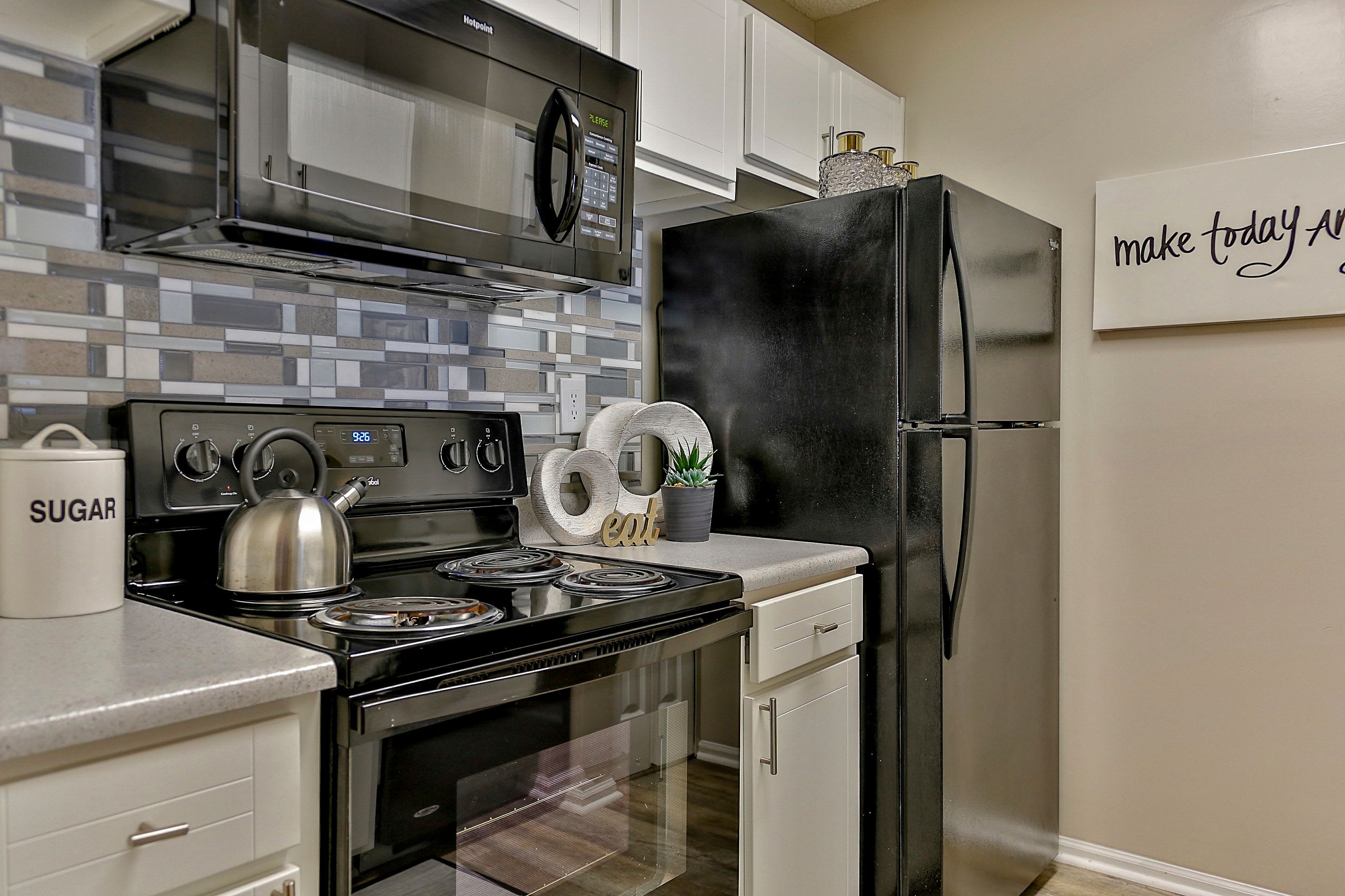 Modern kitchen with granite-style countertops and all-black appliances in model home at Lyric on Bell in Antioch, Tennessee