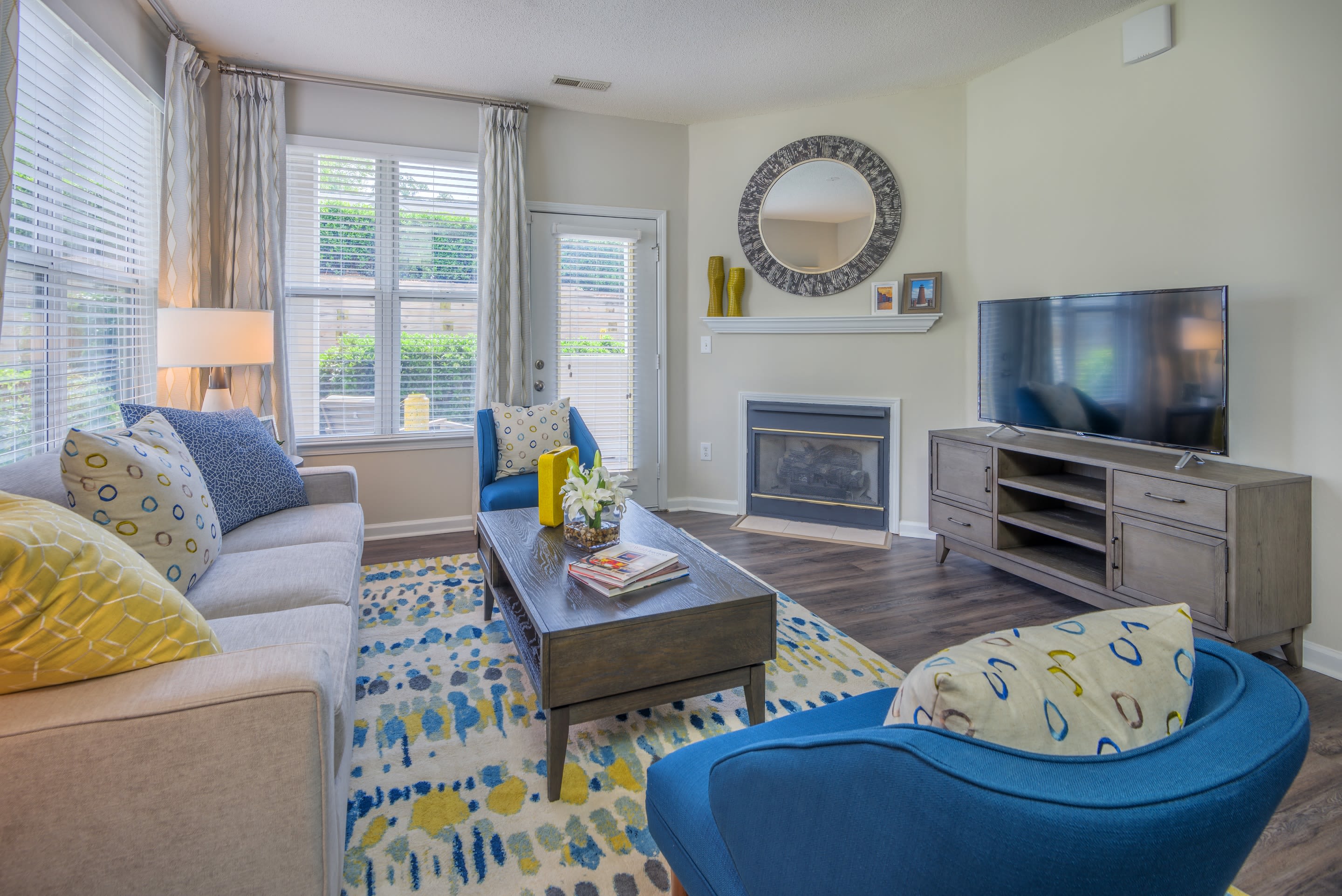 Bay windows and modern furnishings in a model apartment's living area at 200 East in Durham, North Carolina