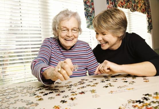 A lady puts together a puzzle with friend at Reunion Court of The Woodlands in The Woodlands, Texas