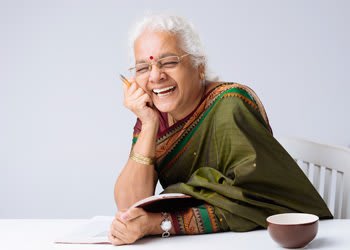 Lady sitting at table with a tea cup laughing