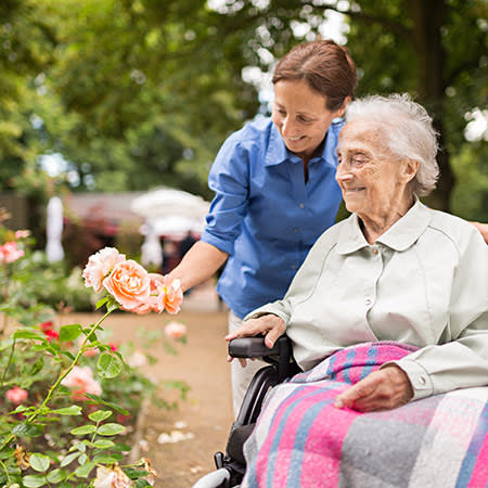 A caretaker and resident looking at flowers at The Legacy at Southpointe Drive in Greenville, South Carolina