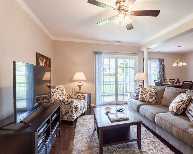 Bright living room with patio access at Oakmonte Apartments in Webster, New York